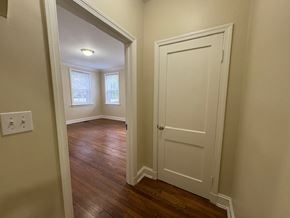 Wilson apartment for rent - A white door is on the right side of a hallway with wood floors.