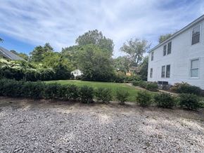 Wilson apartment for rent - A gravel area in front of a white house with a green hedge and trees in the background.