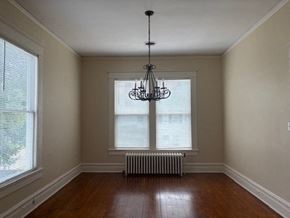 Wilson apartment for rent - A room with a chandelier, a radiator, and a window.