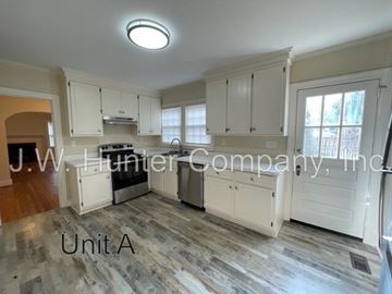 Wilson apartment for rent - A kitchen with white cabinets and a wooden floor.