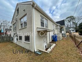 Wilson apartment for rent - A two-story house with a white exterior and a blue trash can in front.