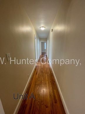 Wilson apartment for rent - A long hallway with wood floors and white walls.
