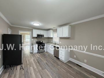 Wilson apartment for rent - A kitchen with a black fridge and wooden floors.