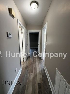 Wilson apartment for rent - A hallway with wood floors and white walls, with a door at the end.
