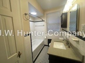 Wilson apartment for rent - A bathroom with a sink, mirror, and bathtub.