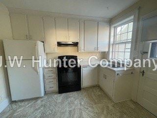 Wilson apartment for rent - A kitchen with white cabinets and a black fridge.