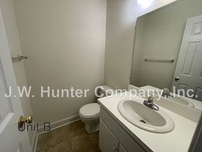 Wilson apartment for rent - A bathroom with a toilet, sink, and mirror.