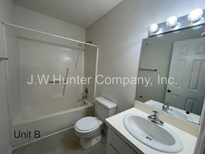 Wilson apartment for rent - A bathroom with a toilet, sink, and mirror.