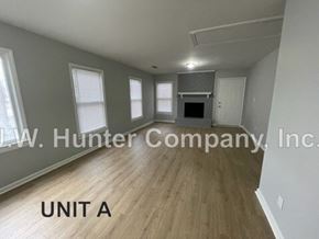 Wilson apartment for rent - A spacious room with wood flooring and a fireplace, labeled as Unit A.