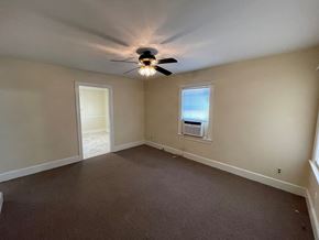Wilson apartment for rent - A room with a ceiling fan and two windows.