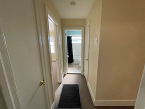Wilson apartment for rent - A hallway with a black mat on the floor leading to a door.