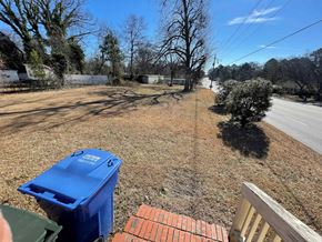 Wilson apartment for rent - A blue recycling bin sits on a grassy area next to a brick wall.