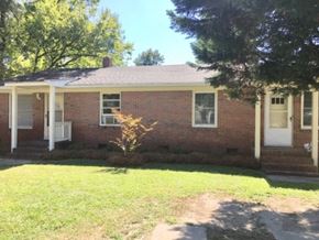 Wilson apartment for rent - A small brick house with a white door and windows.
