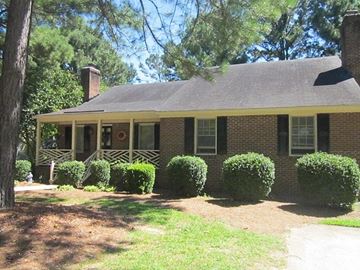 Wilson apartment for rent - a brick house with a porch and some bushes