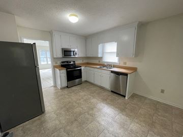 Wilson apartment for rent - A kitchen with a black refrigerator and white cabinets.