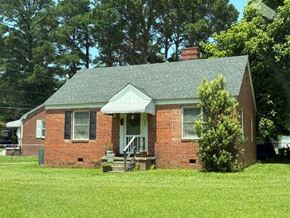 Wilson house for rent - A small red brick house with a green roof and a white door.