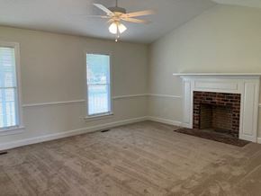 Wilson house for rent - an empty living room with a fireplace and a ceiling fan