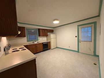 Wilson house for rent - A kitchen with a white counter top and wooden cabinets.