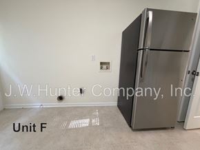 Wilson apartment for rent - A stainless steel refrigerator stands in a room with the text "J.W. Hunter Company, Inc." and "Unit F" on the floor.