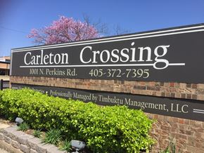 Stillwater apartment for rent - a sign for caliente crossing in front of a brick wall
