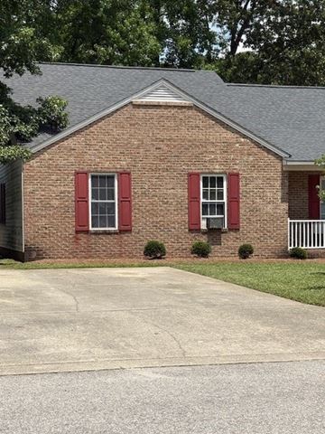 Wilson apartment for rent - A brick house with a grey roof and red shutters.
