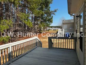 Wilson apartment for rent - A deck with a railing and a view of a backyard with trees.