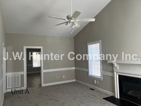 Wilson apartment for rent - A living room with a fireplace and a ceiling fan.