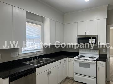 Wilson apartment for rent - A kitchen with white cabinets and black countertops.