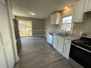 Wilson apartment for rent - A kitchen with white cabinets and a black stove top oven.