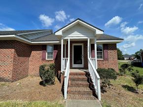 Wilson apartment for rent - A brick house with a white porch and a black door.