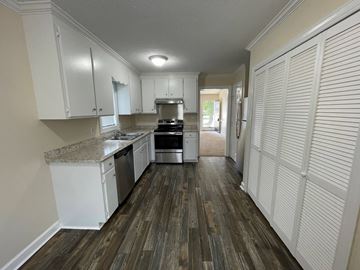 Wilson apartment for rent - A kitchen with white cabinets and a wooden floor.