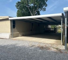 Eunice house for rent - A large garage with a metal roof and a gravel driveway.