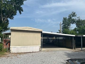 Eunice house for rent - A carport with a tan roof is situated in a gravel driveway.