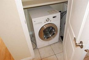 Edmonton apartment for rent - A white washing machine is in a small space under a door.