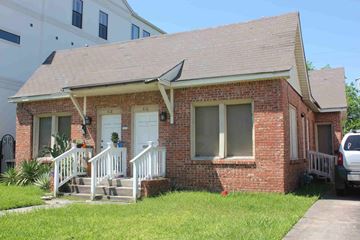 Houston apartment for rent - A small red brick house with a white door and a white porch.