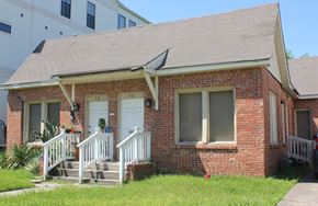 Houston apartment for rent - A small red brick house with a white door and windows.