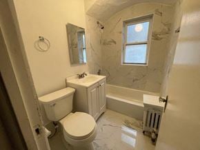 Chicago apartment for rent - A white toilet sits next to a sink in a bathroom with a window.