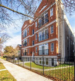 Chicago apartment for rent - A red brick building with a black fence in front.