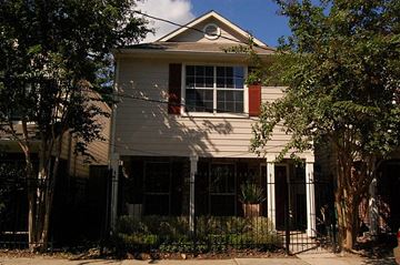 Houston house for rent - A house with a red window trim and a black gate.