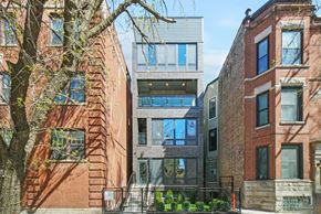 Chicago apartment for rent - A modern building with glass windows is situated between two older brick buildings.