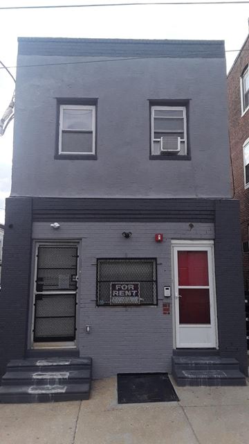 Philadelphia apartment for rent - A grey building with a red door and a sign that says "For Rent".