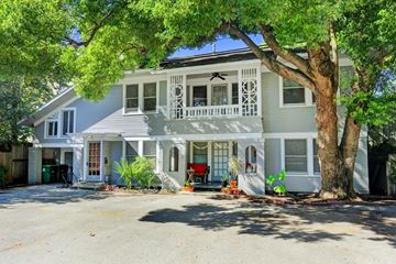 Houston apartment for rent - A white house with a grey roof and a tree in front.