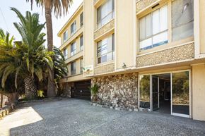 Oakland apartment for rent - A building with a stone wall and a palm tree in front.