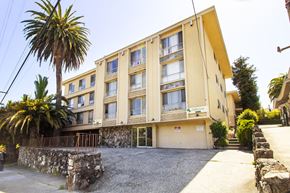 Oakland apartment for rent - A yellow building with a stone wall in front.