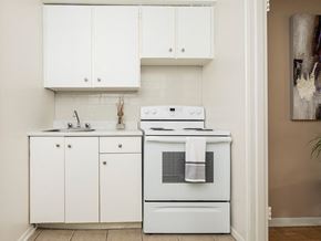 Ottawa apartment for rent - a kitchen with a stove and sink and white cabinets
