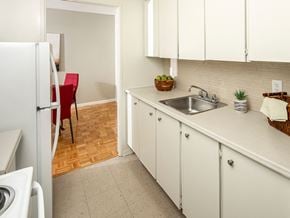 Ottawa apartment for rent - a kitchen with white cabinets and a sink and a refrigerator