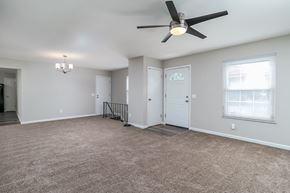 Florissant house for rent - A spacious room with a ceiling fan and carpeted floor.