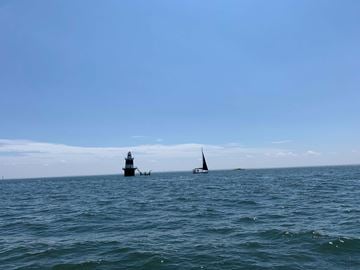 Atlanta apartment for rent - A lighthouse stands in the distance on a calm sea with a sailboat nearby.