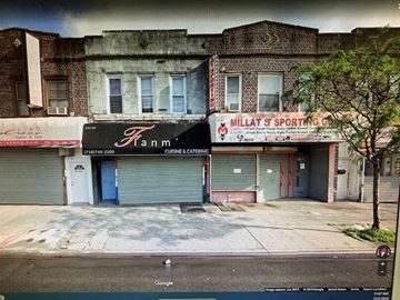 Queens apartment for rent - A street view of a building with a closed blue door and a sign that says "Fann".