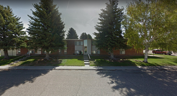 Pine Bluffs apartment for rent - A street view of a residential area with houses and trees.